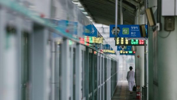 地铁车厢里乘客单手握着手机观看黑桃tv，屏幕光映在脸上，车厢灯光偏冷、画面安静